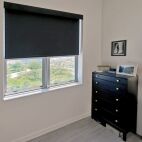 black fabric blackout roller shades in guest bedroom with black fascia